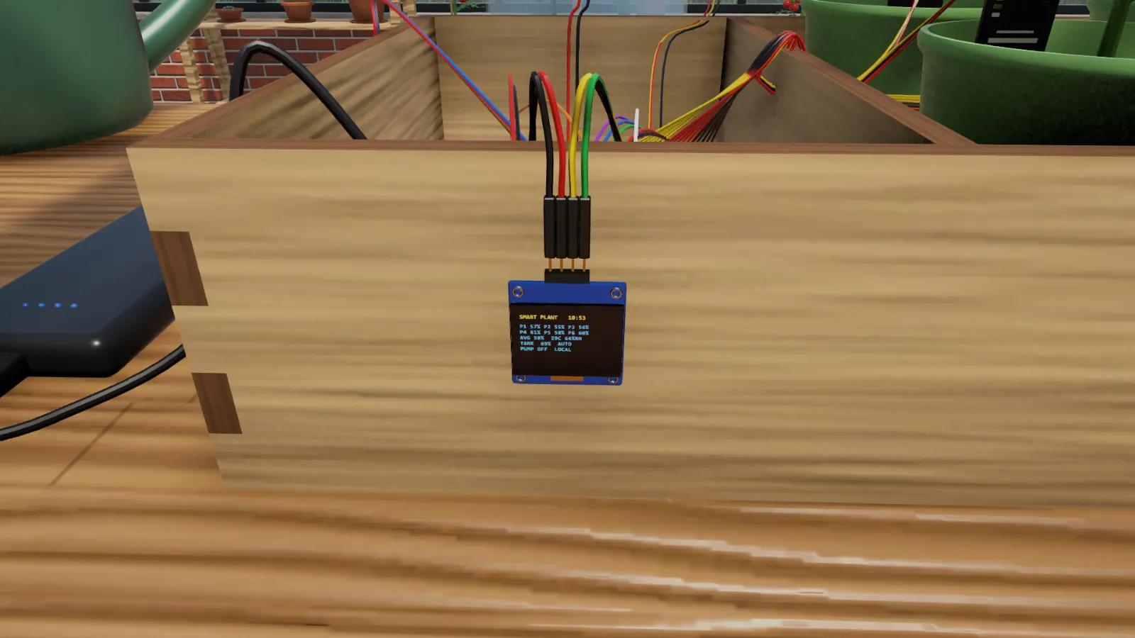 The small OLED display wired to the side of the planter box.